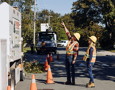 Workers taking safety precautions while performing their tasks. They are wearing protective helmets and jackets to ensure safety.