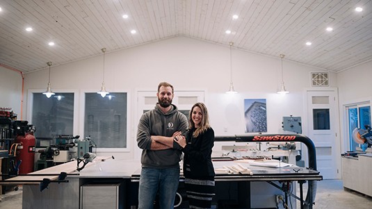 Two contractors smiling in front of building plans.