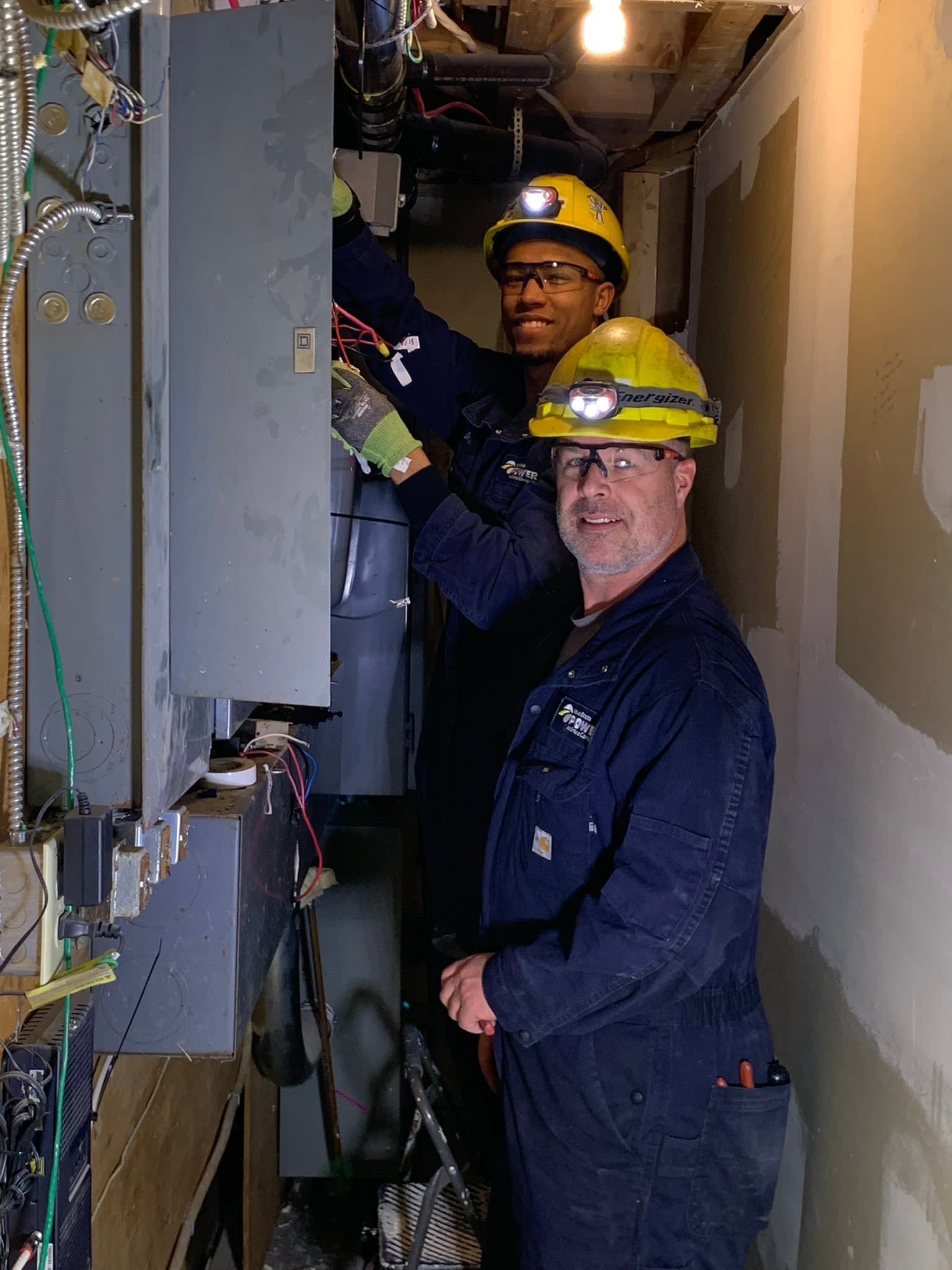 Two workers inspecting an electrical panel
