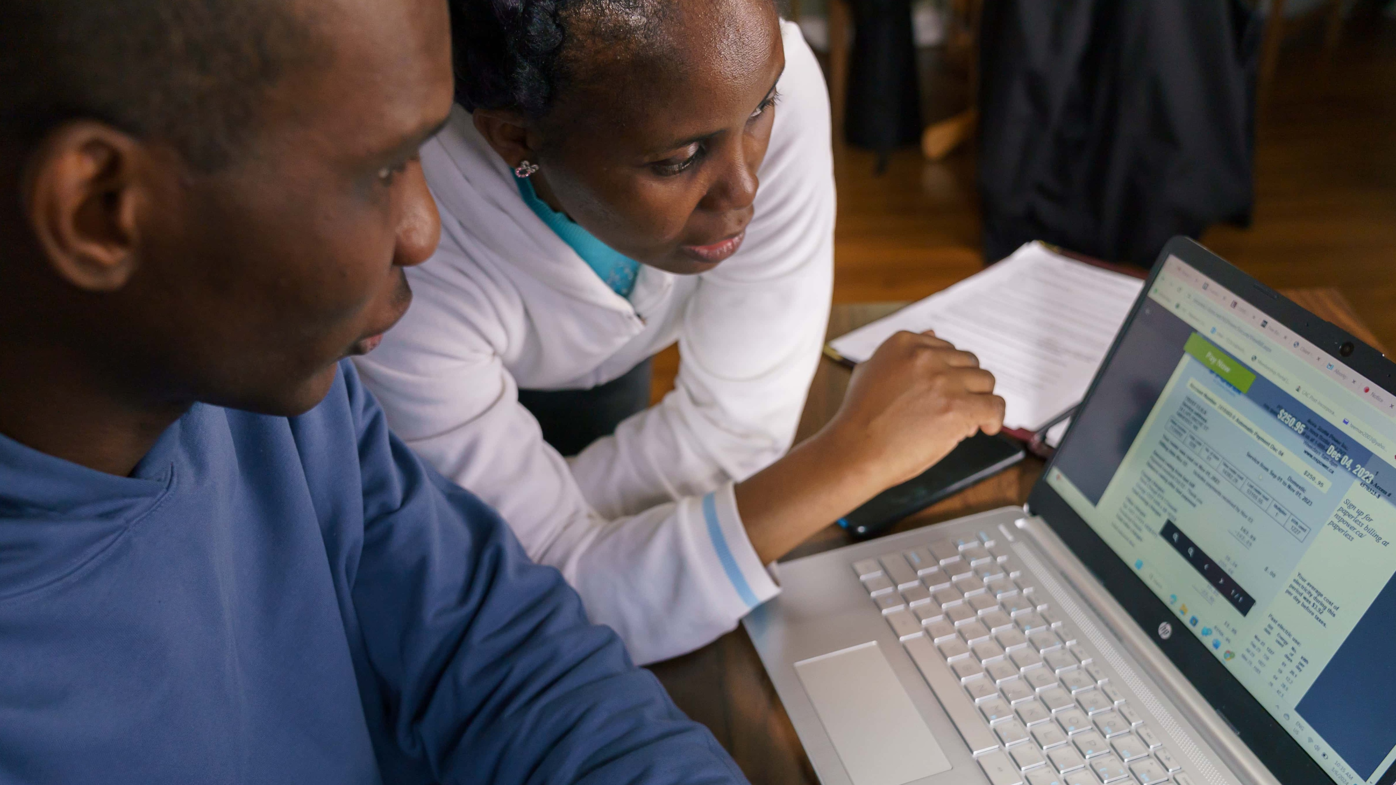 two people looking at a computer screen displaying a power bill